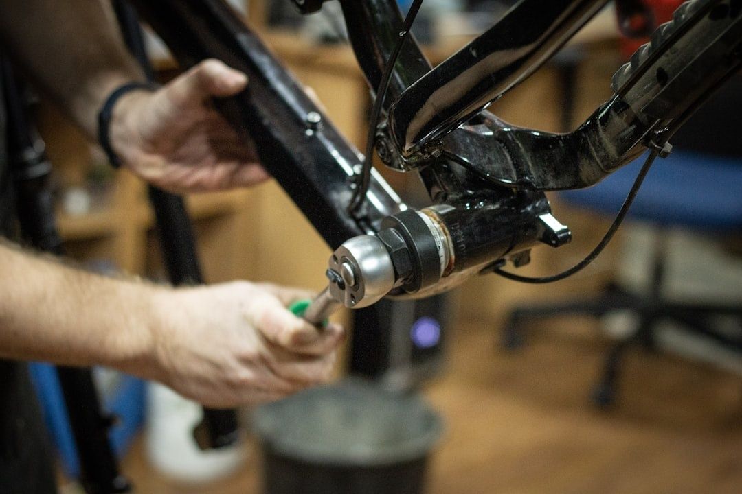 Mekaniker justerer en cykelramme med håndværktøj på værkstedet